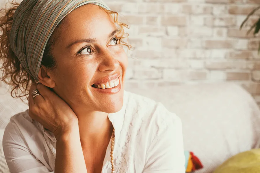 A smiling middle-aged woman sits on her couch. Schedule bioidentical hormone therapy for women from Blue Skye Health and Wellness in Tampa.