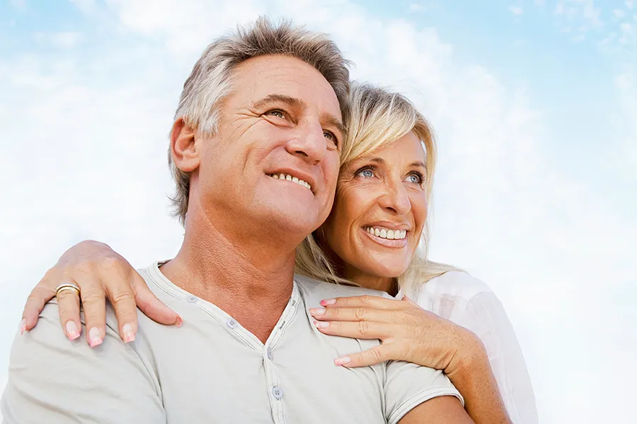 A mature couple embraces outside under the sky. Get CJC 1295 anti-aging peptides from Blue Skye Health and Wellness in Tampa.