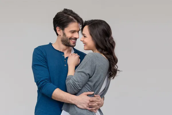 A man in a blue shirt embracing a woman in a gray shirt smiles due to his successful erectile dysfunction care from Blue Skye Health and Wellness in Tampa.