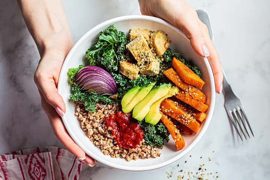 A bowl of vegan salad with baked vegetables, avocado, tofu and buckwheat. Schedule gut health and digestive issues treatment from Blue Skye Health and Wellness in Tampa.
