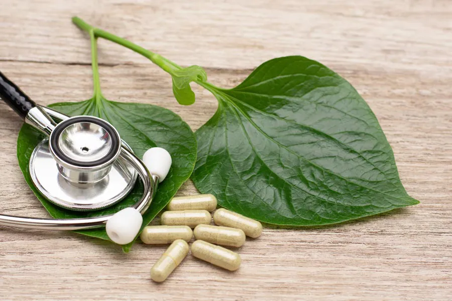 A stethoscope, leaves, and medicine capsules on a wood table, representing Integrative Medicine provided by Blue Skye Health and Wellness in Tampa.