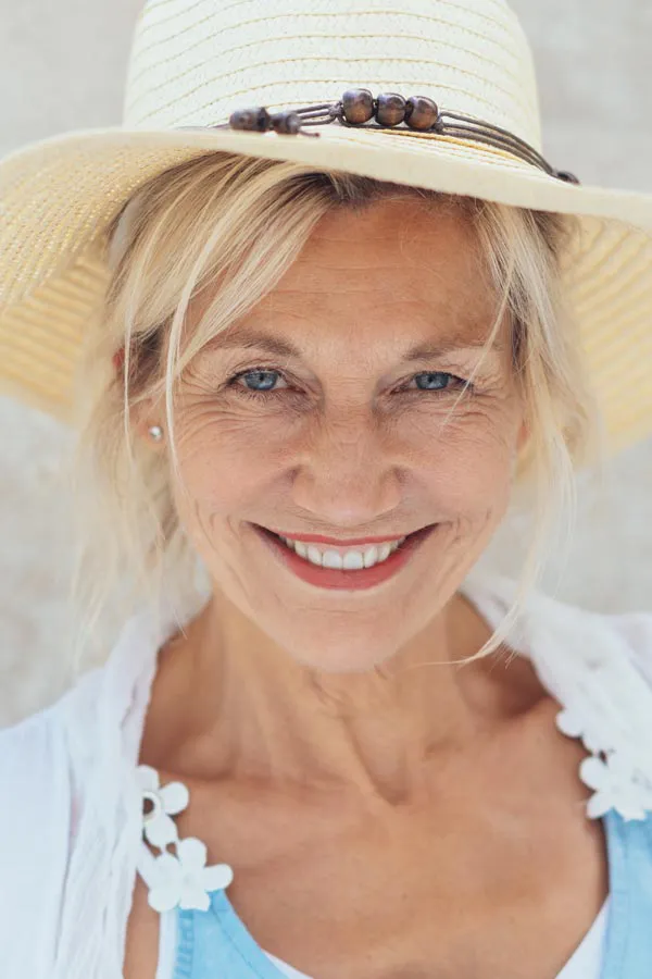 A beautiful, smiling older woman with blonde hair and a sunhat, happy with menopause treatment from Blue Skye Health and Wellness in Tampa.
