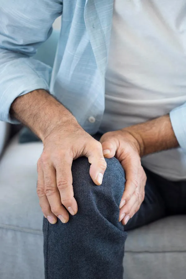 A close-up of a man holding his knee while experiencing pain from osteoporosis. Get osteoporosis treatment from Blue Skye Health and Wellness in Tampa.