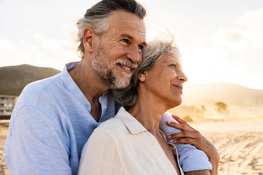 A mature couple at the beach warmly look out onto the ocean. Get osteoporosis treatment from Blue Skye Health and Wellness in Tampa.