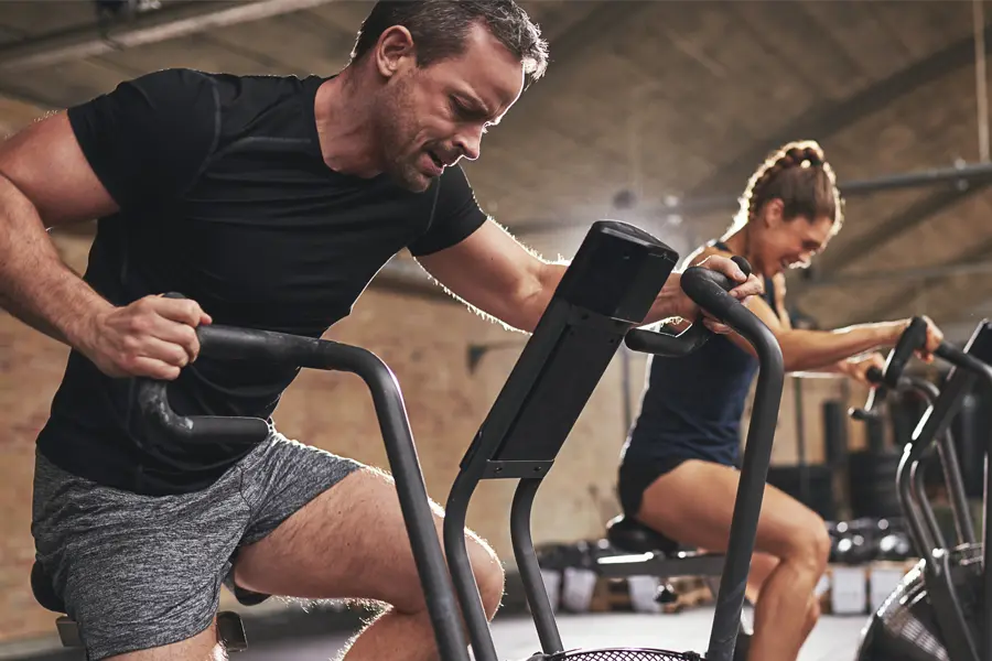 A couple in a brick gym work as hard as they can on exercise bikes, inspired by successful Tirzepatide treatment from Blue Skye Health and Wellness in Tampa.