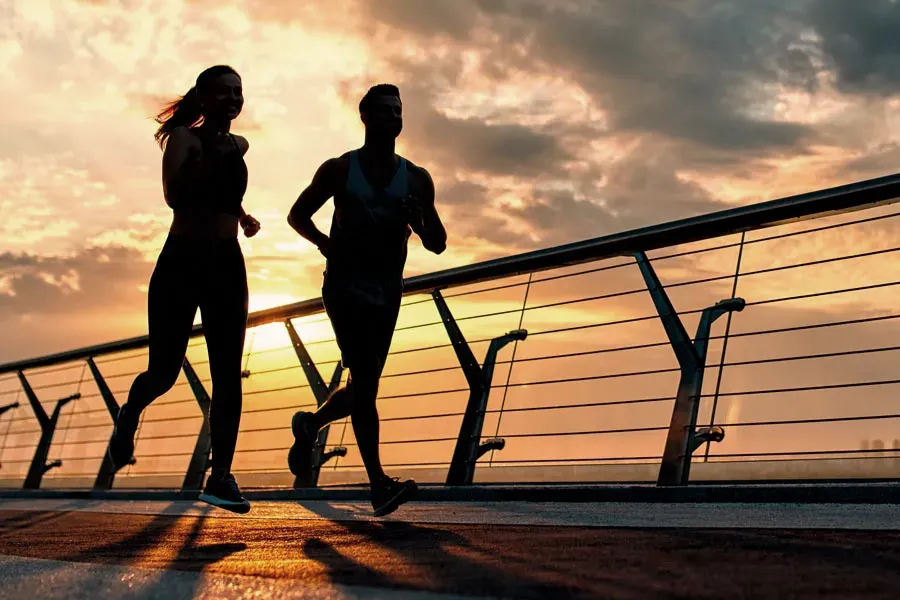 A couple running, silhouetted by the sunrise. Get weight loss treatment from Blue Skye Health and Wellness in Tampa.
